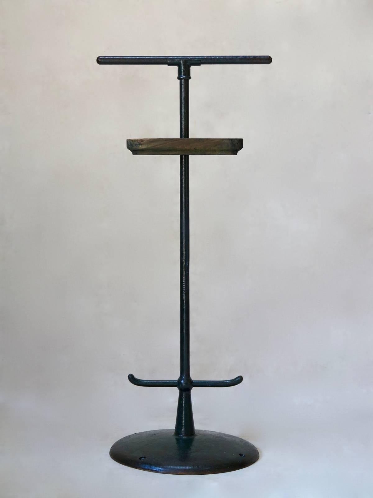 Chic pair of streamlined, cast-iron valet stands, with wooden vide-poches. The iron has a lovely textured feel and retains its original, dark green paint finish. The use of cast-iron, as well as the four holes around the base to fix the pieces to