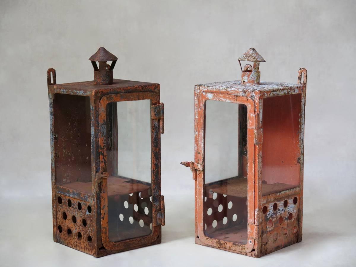 Large pair of very sturdy and heavy, painted iron lanterns, used by the French train service the SNCF, circa 1930s. They have glass fronts and sides, and iron backs. The bottom section is perforated, and they have little chimneys on the top. Can be