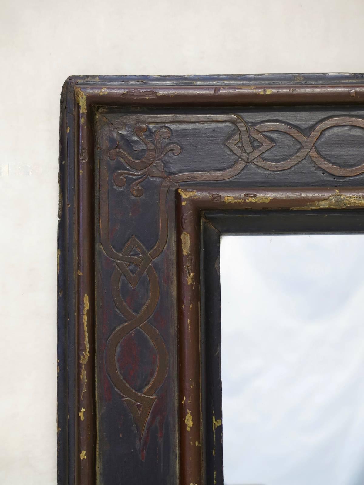 Chic 19th century ebonized wood frame engraved with a geometric design. Fitted with a mirror. The back has been sealed with a collage of antique papers.