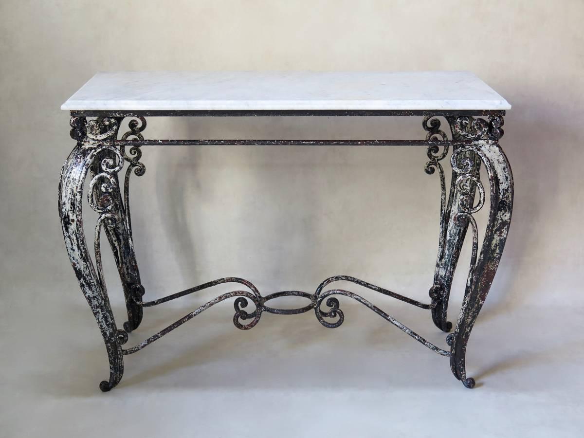 Rare, lovely quality, heavy wrought iron console table with original marble top. The base features large cabriole legs adorned with curlicue details, and ending in elegant scrolled feet. Pretty stretcher. Original paint: black, with an earlier white