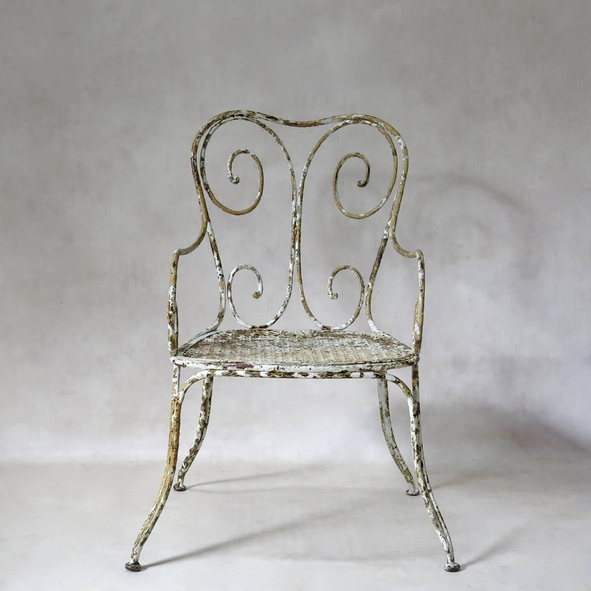Very elegant, unusually wide, painted wrought iron garden chair. Sturdy, heavy and beautiful. Yellow and white paints visible.