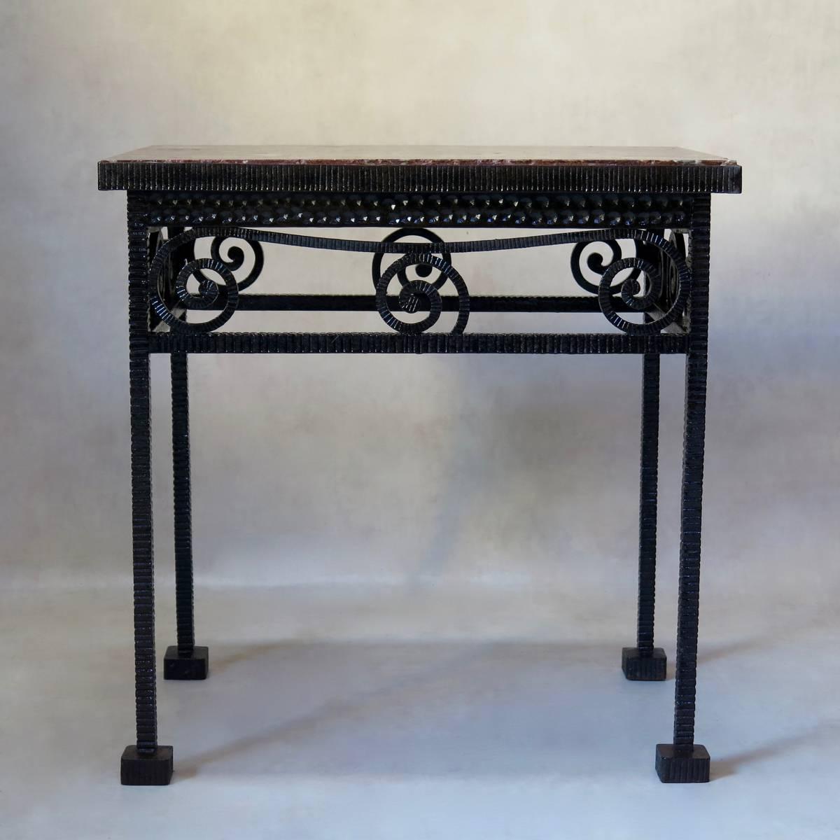 Unusual French, 1930s table with a heavy, hammered iron structure. The ironwork is patterned all over with a ridged effect, except for the apron, which has a decor of small imprinted dots. Curlicue motif on apron. Raised on slender square legs,