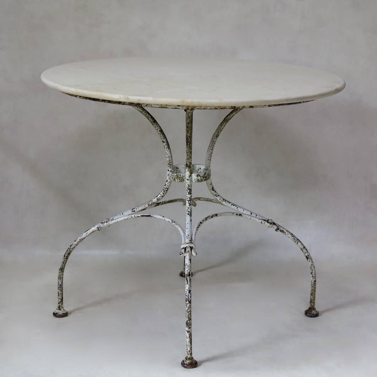 Elegant garden table with a rather unusual and lovely base and a round, off-white marble top. Original paint.