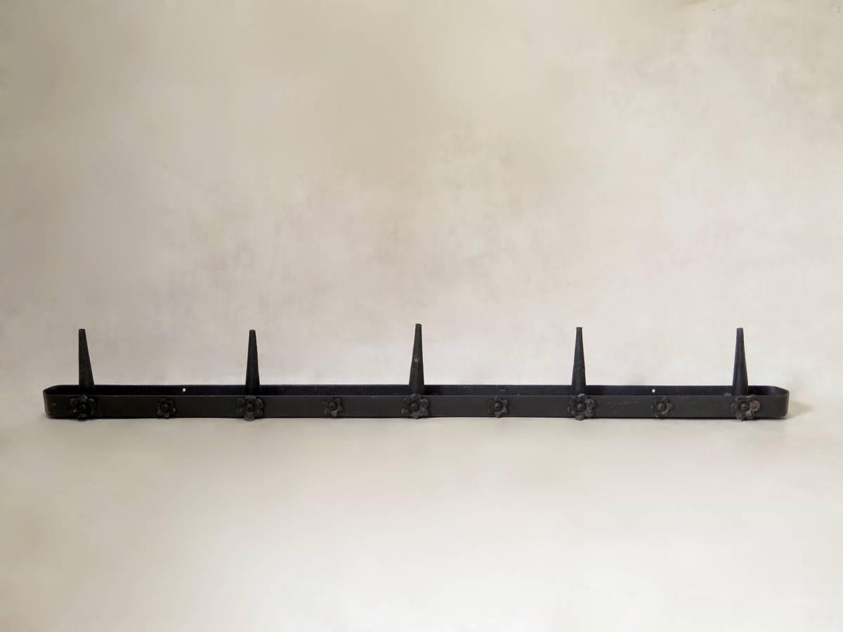 This elegant pair of long and heavy wrought iron candle-holders holds five candles each; and are decorated with floral rosettes on their fronts. Can also be fixed to a wall.