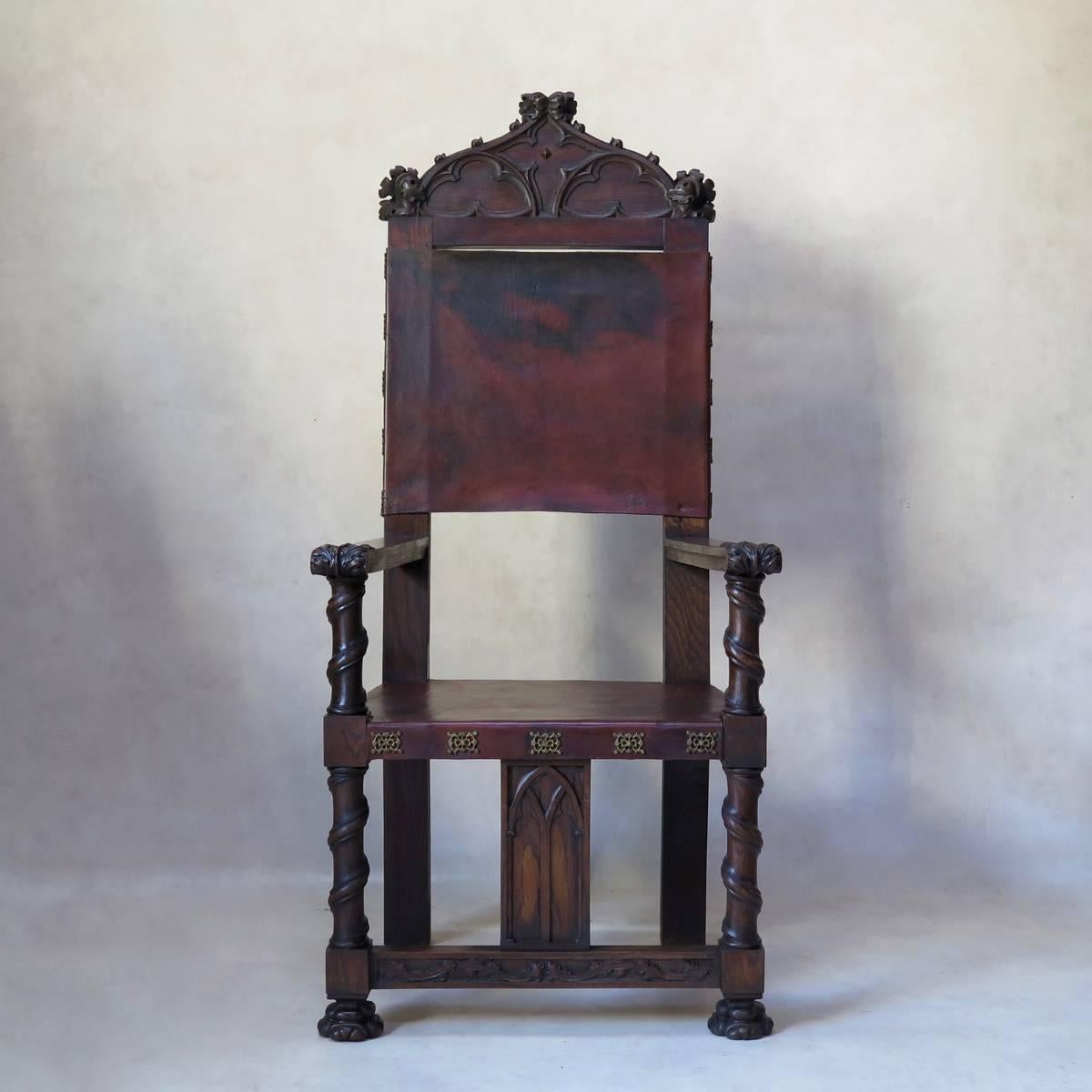 Imposing pair of medieval / Gothic style armchairs, in carved oak, with leather seats and backs. Ornate brass trim.