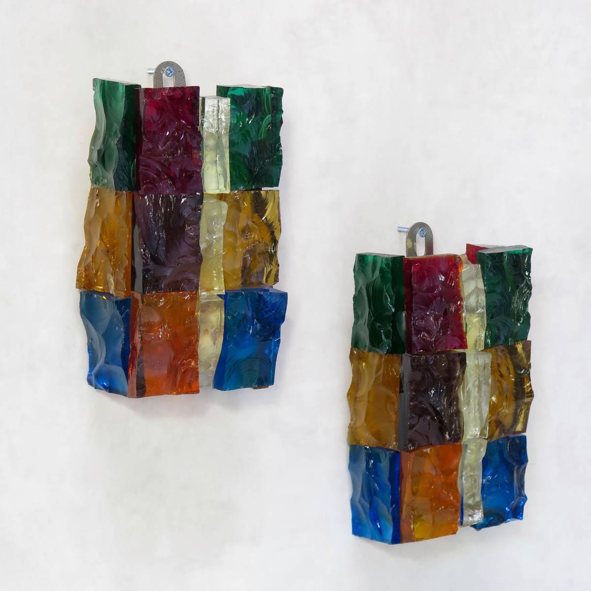 Pair of heavy, glass, "Brutalist" style sconces with a rough-hewn exterior, made of various colorful glass pieces, assembled together. The inside is smooth.