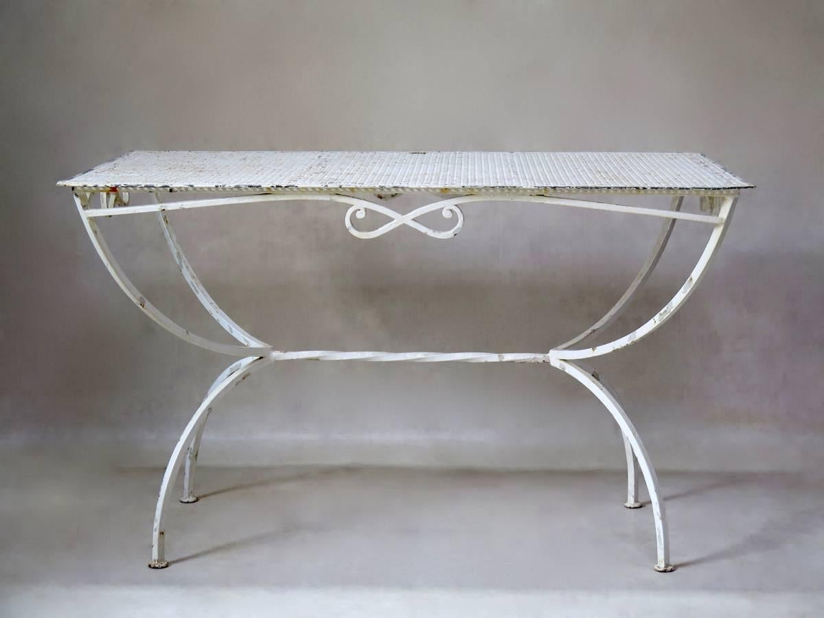 Wrought iron, bow-motif painted garden or outdoor dining table. The top is made of cloverleaf-patterned sheet metal. Curule-style base, with a bow-motif apron and twisted iron stretcher.
Nice quality.