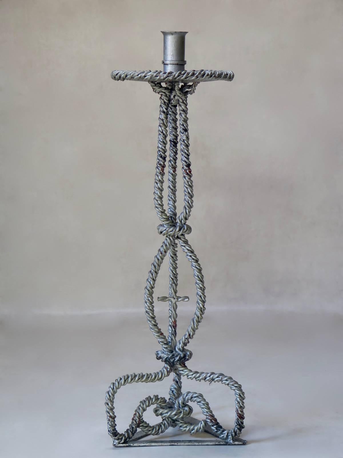 Unusual Folk Art candleholder made of twisted iron, painted silver. Triangular base, adorned with a cross.
