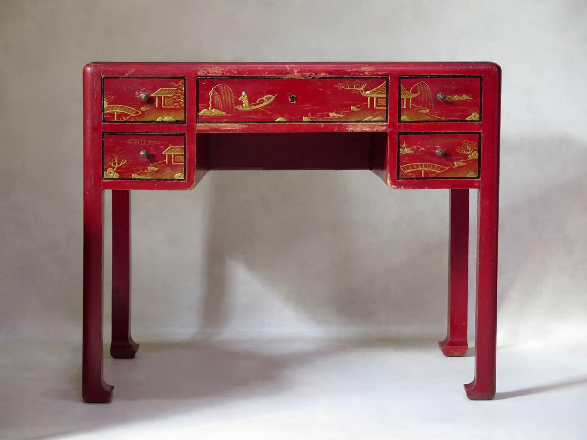 Chinese-style Art Deco writing set comprised of a desk, a barrel-back armchair and a table lamp, attributed to Paul Poiret's fashionable furniture-making firm, Atelier Martine. Red lacquer, with chinoiserie decor on the desk front and top and on the