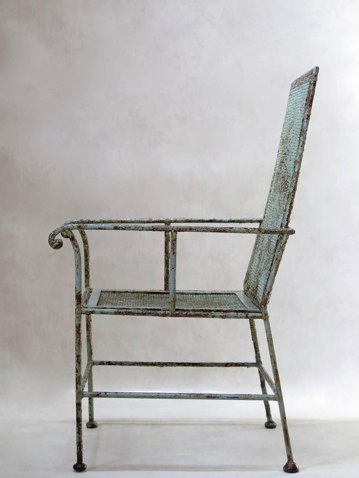 Beau fauteuil en fer forgé au design inhabituel et assez géométrique, avec sa belle peinture verte d'origine. Le dossier légèrement incliné est réalisé avec un treillis métallique à mailles complexes, et l'assise avec un treillis métallique à