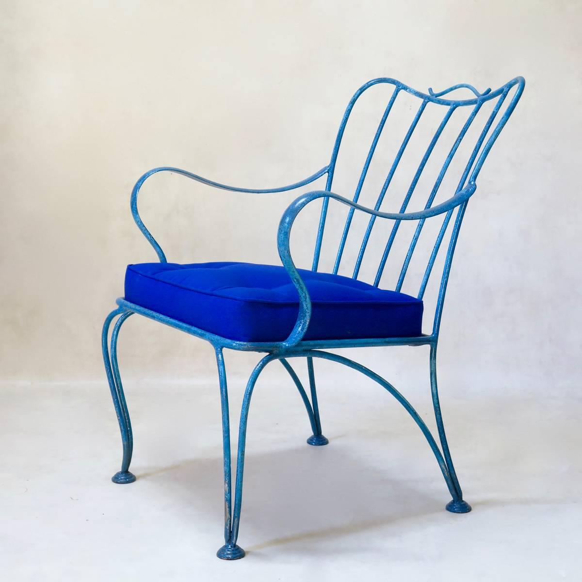 Set of four wide and comfortable outdoor lounge chairs of nice proportions, in striking blue-painted wrought iron, with royal blue canvas seat cushions. Cabriole front legs, and splayed back legs. Gerat lines.