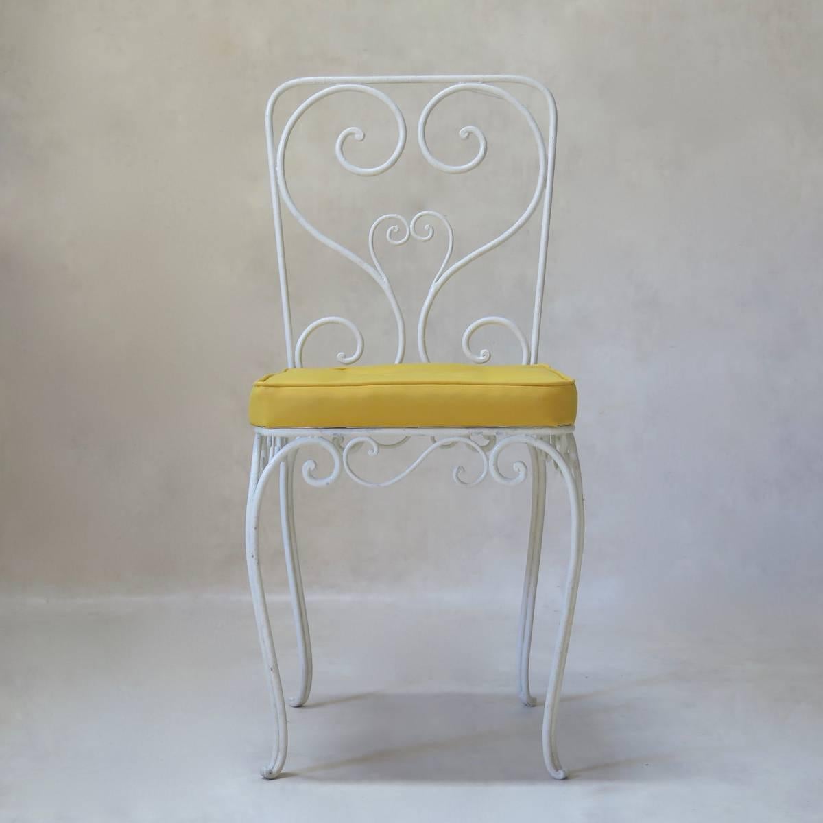 Very elegant set comprising two chairs and two armchairs, made of wrought iron, with scrolling and curlicue motifs, raised on cabriole legs. Seats in bright, yellow canvas (outdoors).

Dimensions provided below are for the armchairs. The chairs