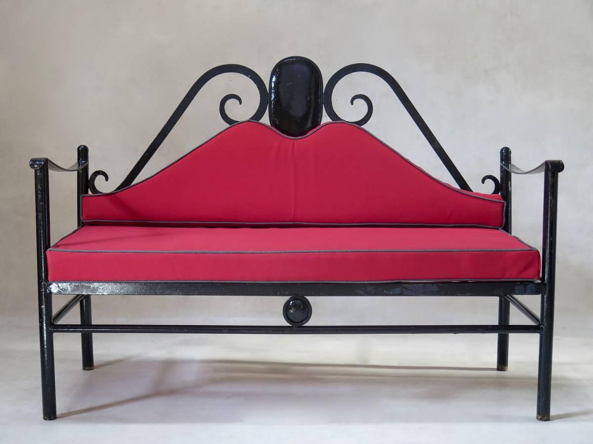 Pair of unusual, rather baroque, painted iron settees, with red canvas-upholstered seats and backs.