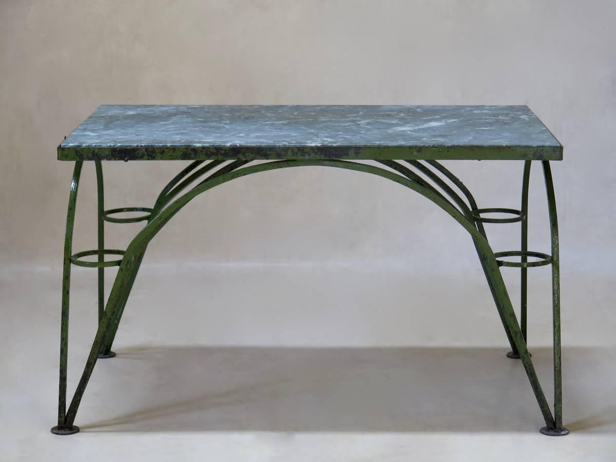 Unusual rectangular coffee table, the base made up of a series of six arches, giving the table a dynamic feel (an arch at each side, and two intersecting ones, making up a stretcher of sorts). The tripod feet are adorned with circles. The green