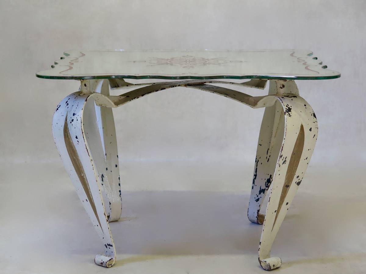 Pretty iron coffee table, raised on cabriole legs, with a scallop-edged églomisé mirror top. The base is painted in original cream color, with gold accents.