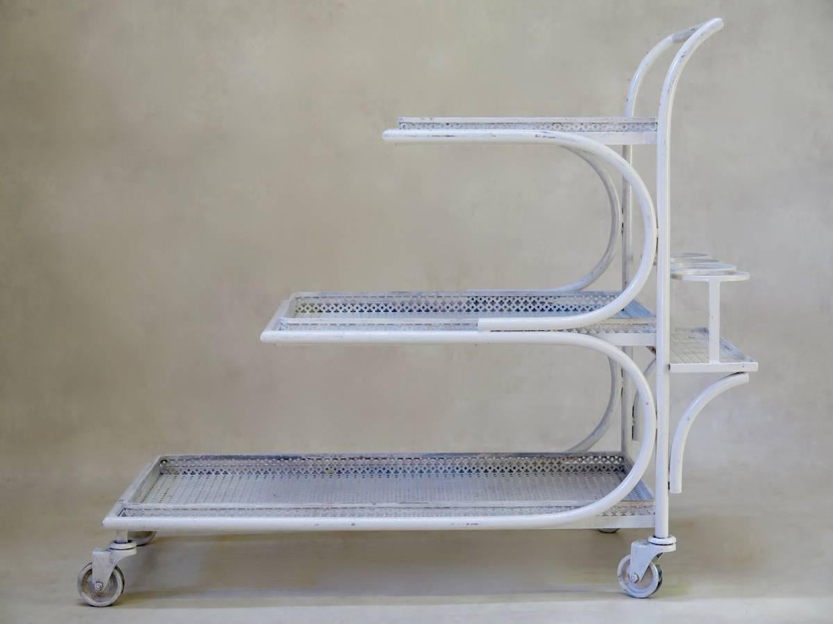 Elegant, tiered drinks' trolley comprising three removable trays of cloverleaf-patterned sheet metal, so typical of the 1950s. Fitted with a bottle-holder at the back. Nice design, with graceful lines.