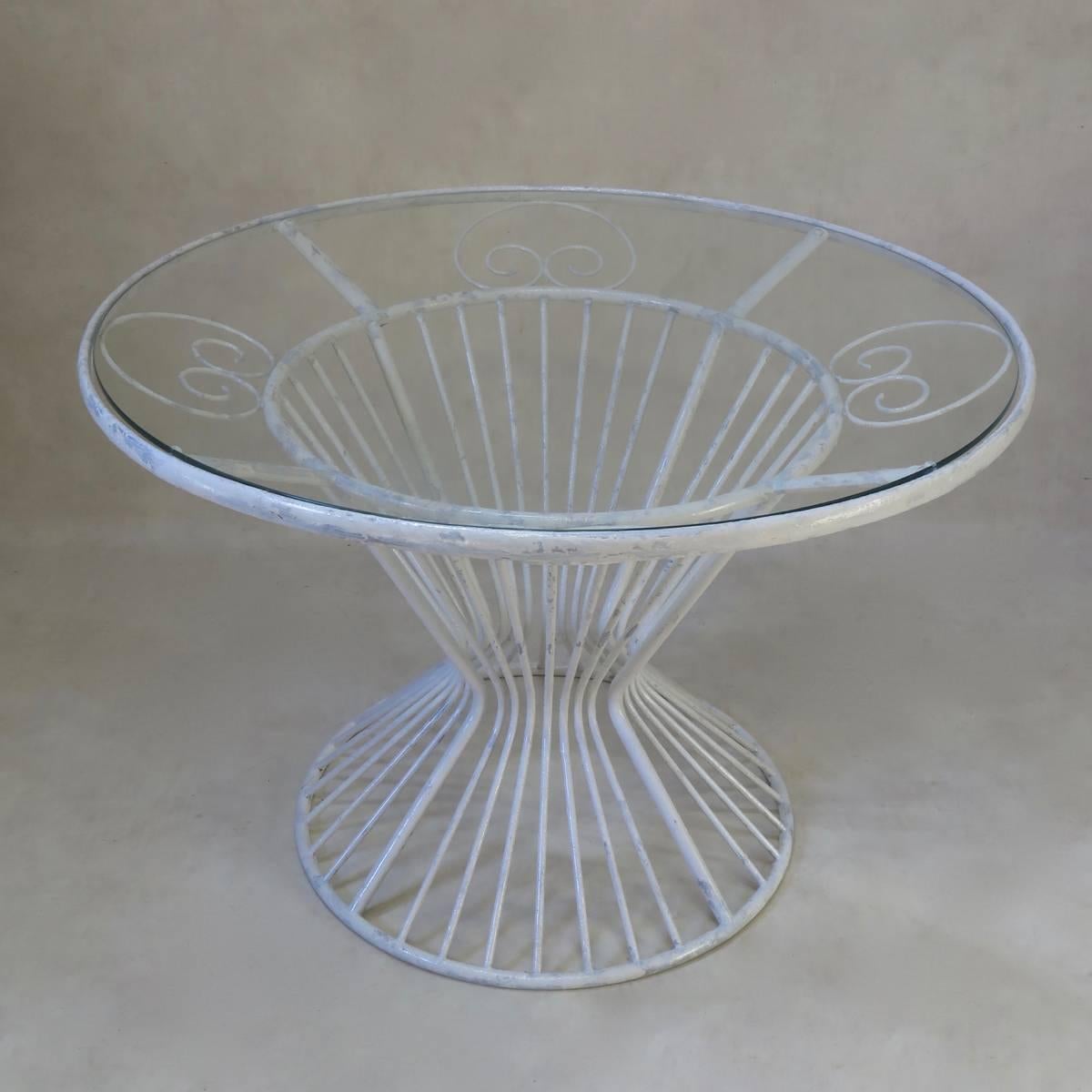 A French, circa midcentury round dining table of nice design, made of painted iron, and fitted with a safety glass top.