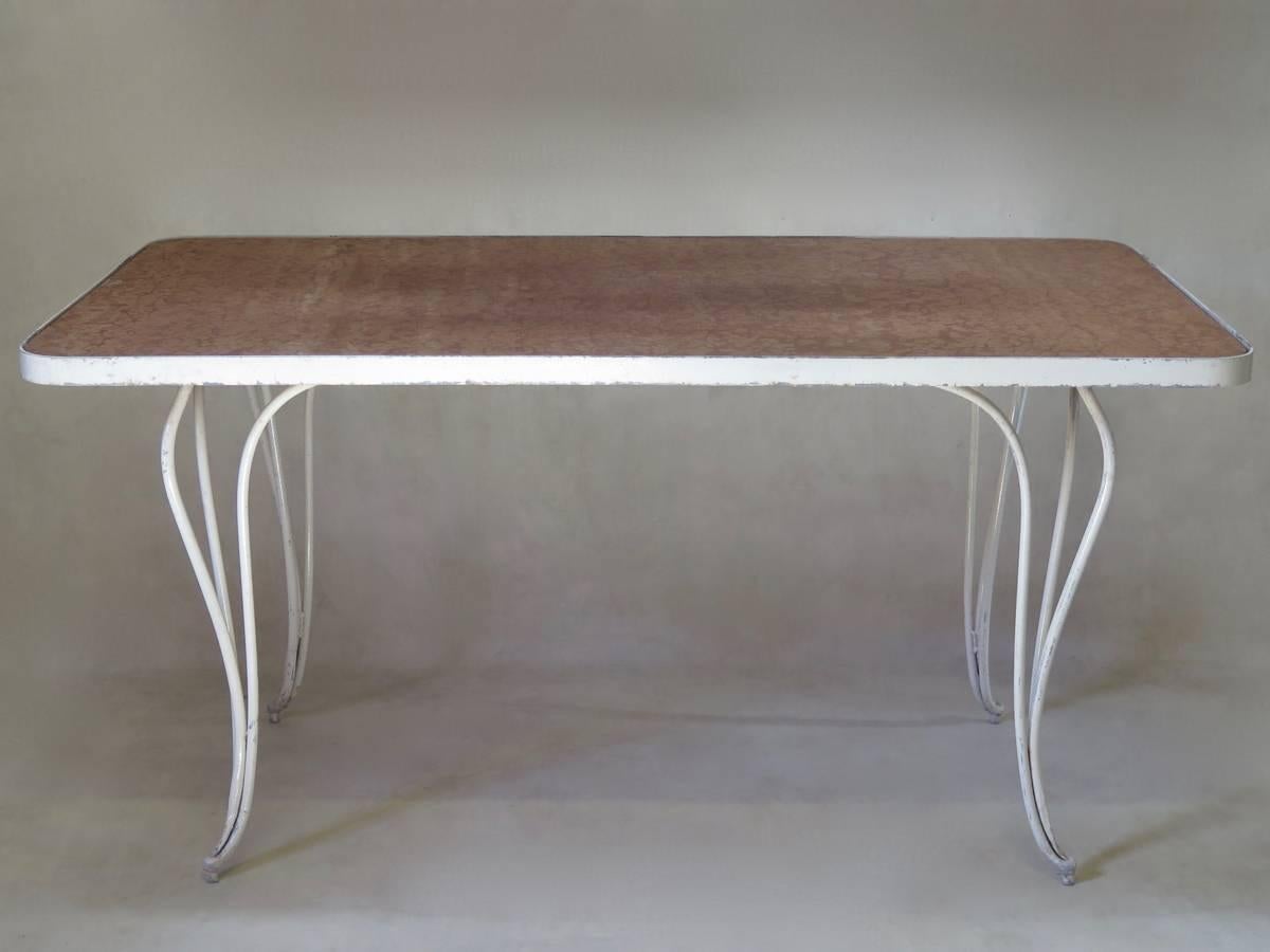 Elegant Art Deco table with a painted iron structure. The top, with rounded corners, is made of a thick slab of pink marble, which slots into the apron. Raised on cabriole legs, each made up of three rods which taper down to a slender foot.