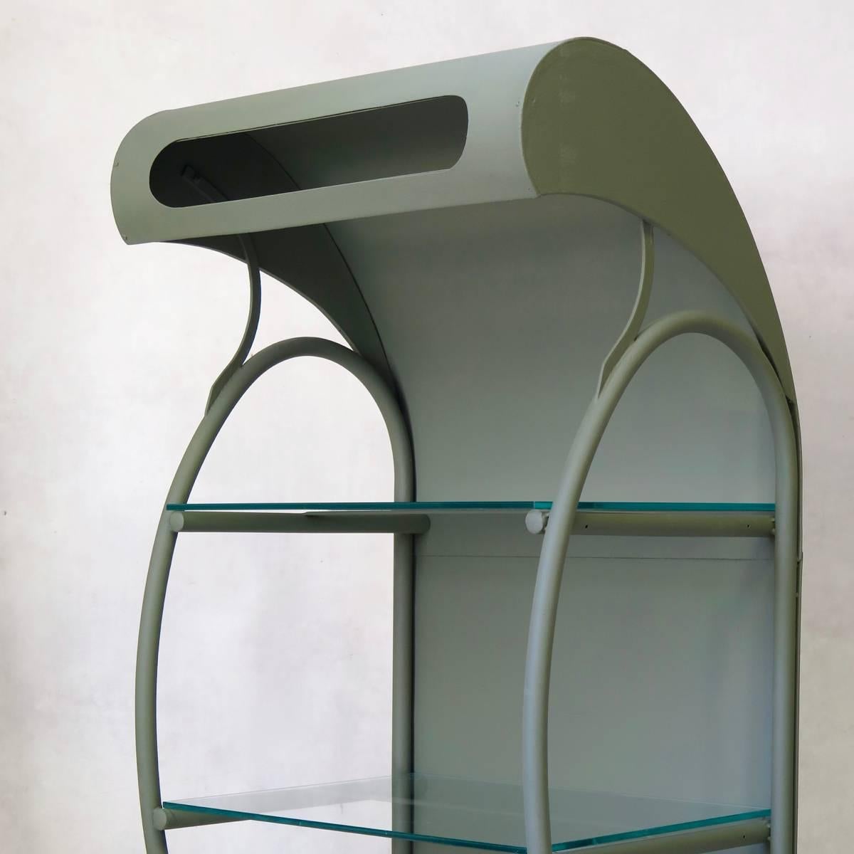 One-of-a-kind pair of custom-made shelvings units, with a hooded metal top, and glass shelves, painted a green/grey color.