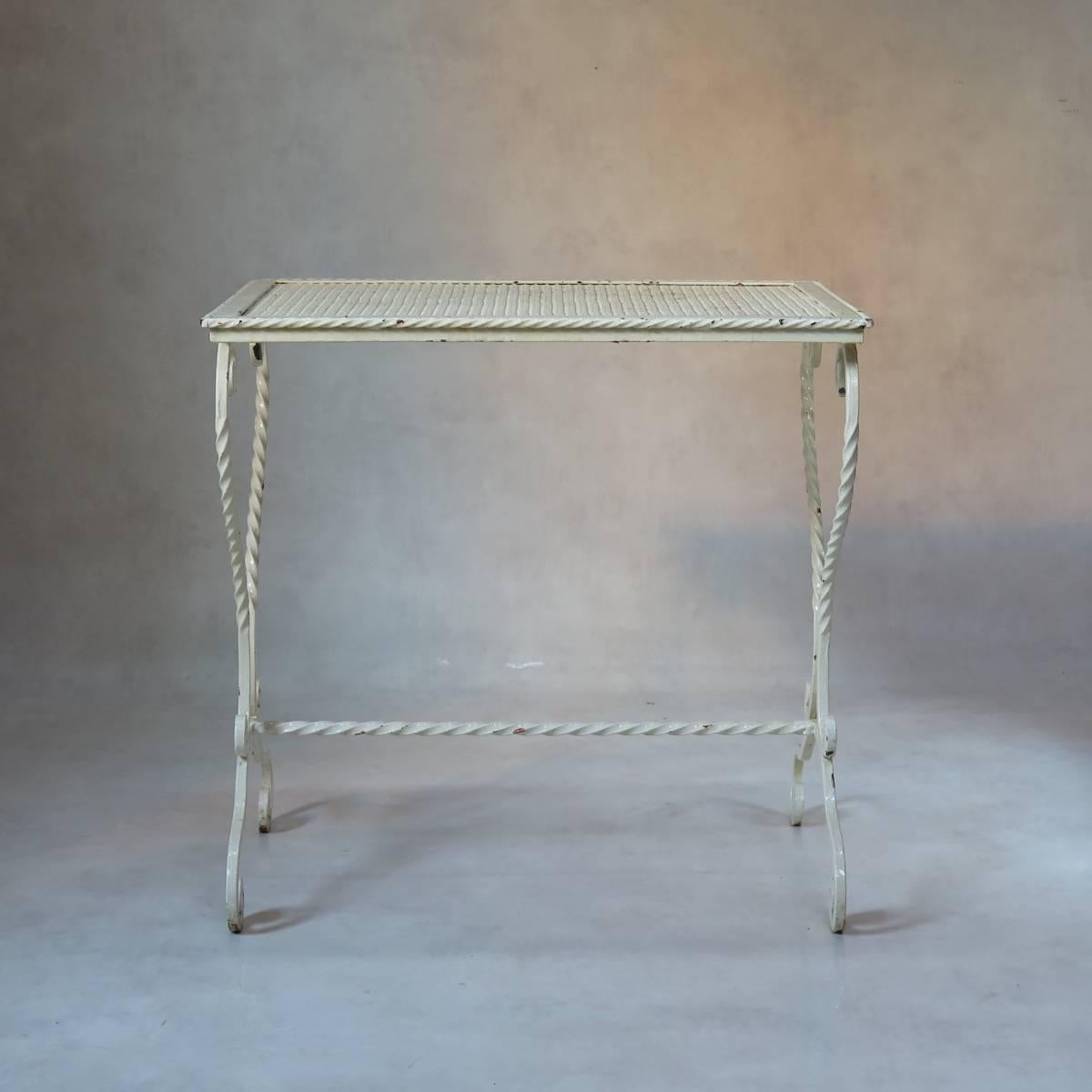 Painted wrought iron garden table with a cloverleaf-patterned top with a twisted iron surround and an elegant scrolled base.