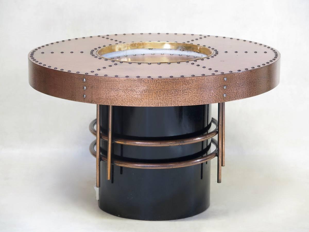 Fun pair of round coffee tables with a drop center. The tops are covered in sheet copper with a patinated effect and nailhead trim, and the bases are black-painted metal, with decorative copper tubing. The switches on the bases used to be for