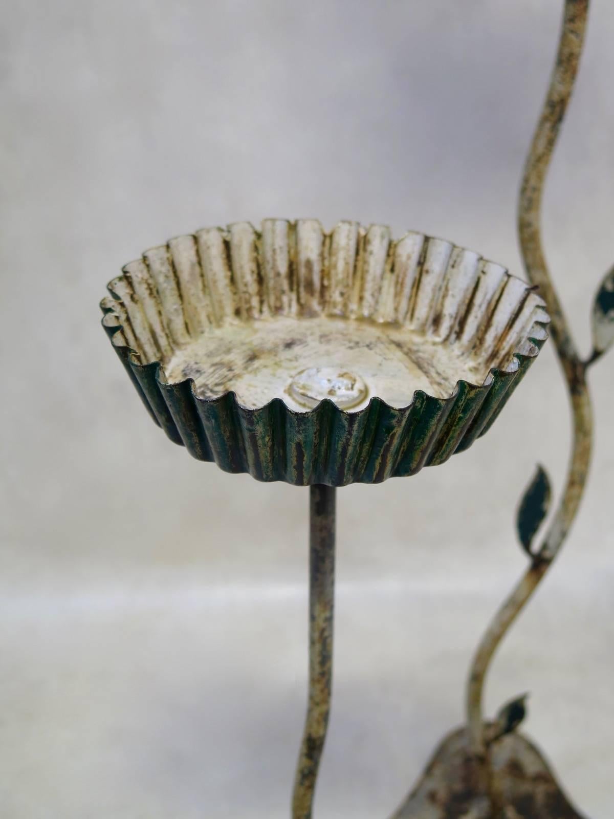Unique set of five handmade Folk Art iron candleholders, raised on wavy triangular bases, with tall stems adorned with leaves along their lengths, and topped with large, flat candleholders with crimped edges. Traces of original white and green