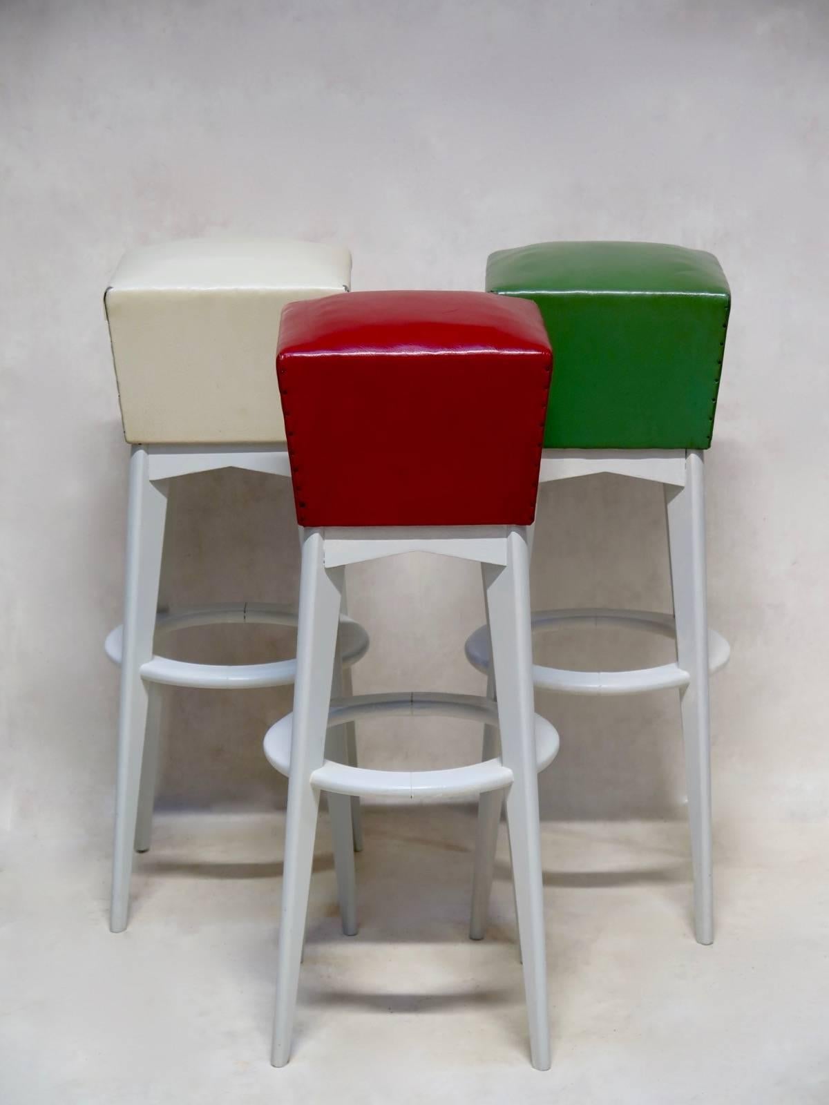 Chic and fun set of six mid-20th century bar stools. The seats are covered in the original red, green and cream-colored vinyl, leatherette-type upholstery. They are raised on slender, tapering and splayed legs, joined by a circular stretcher or