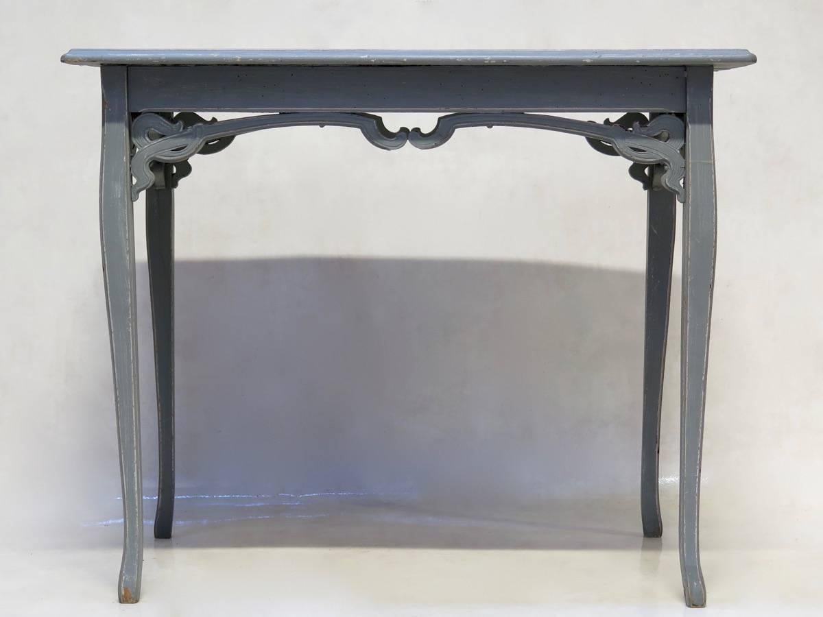 Hübsch bemalter Holztisch mit einer geschnitzten Schürze im Jugendstil. Die Farbe ist grau-blau.