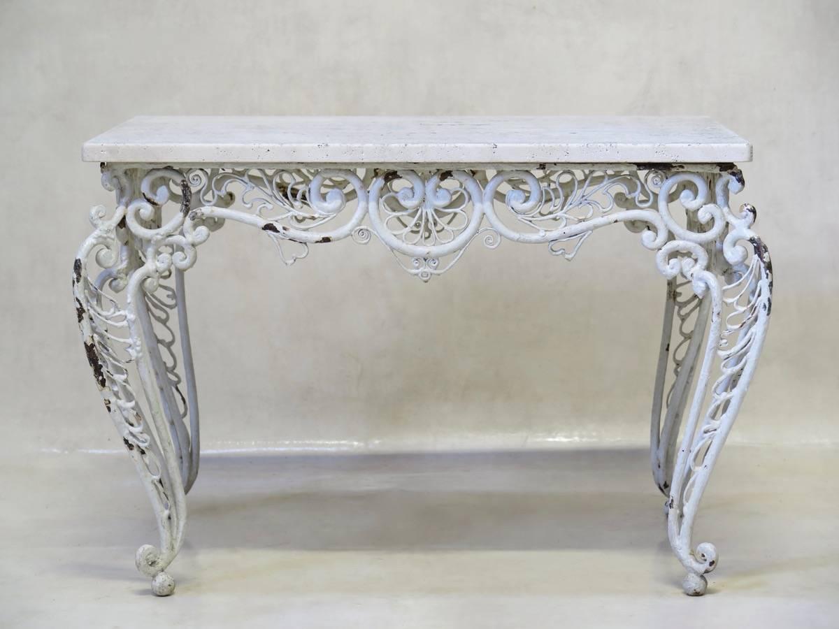 Petite table with a heavy base displaying gorgeous fretwok iron detailing throughout, finished in thick coats of white paint. Travertine top.