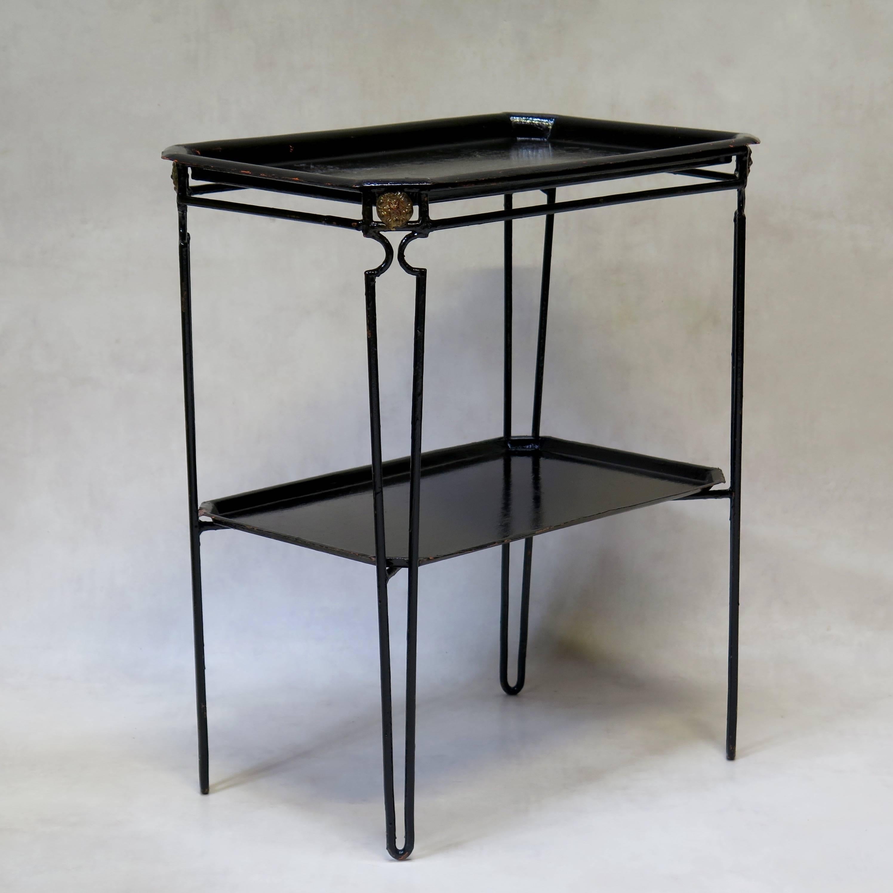Neoclassical style set of four metal tray tables painted glossy black with traces of orange primer visible beneath. 
The two highest side tables have removable trays (top and bottom). They end in slightly different feet.
The larger and lower