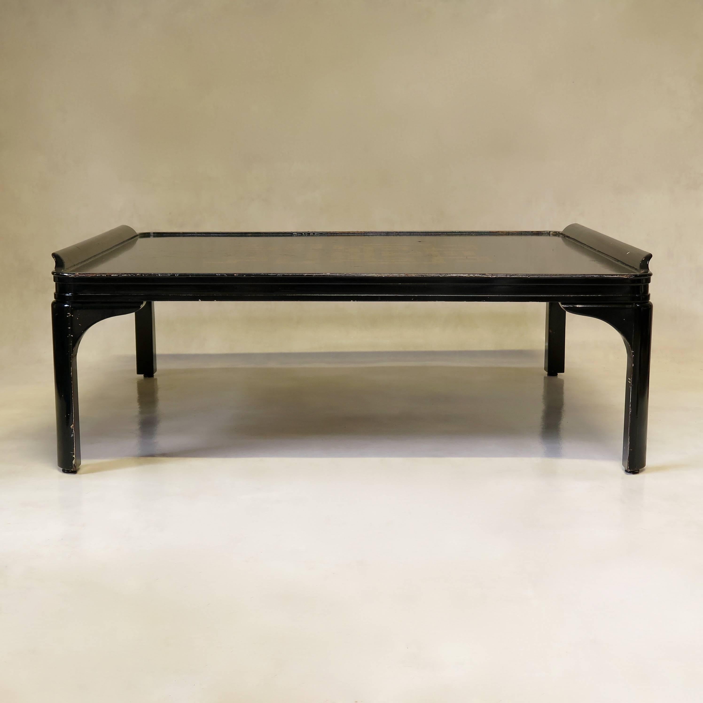 Chic and sleek black-lacquered Art Deco style low square table with a gold geometric motif in the center of the table top. 
Raised and outward-curving edges on two sides of the top.
Unusually large in size.