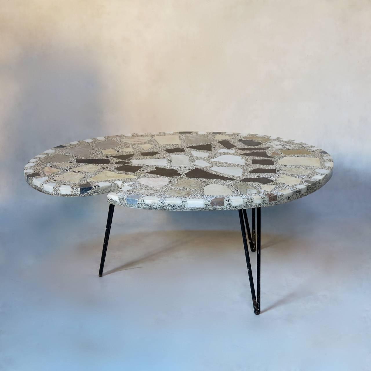 An unusual French mid-century coffee table with a marble terrazzo top, shaped like an artist's palette. Raised on three iron hairpin legs.
