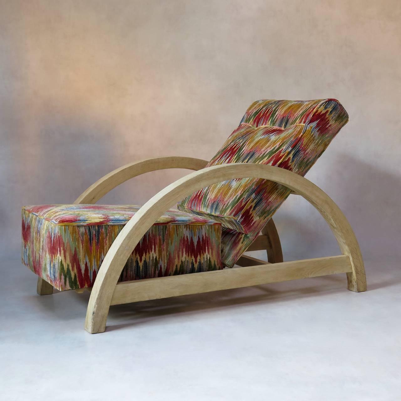 Large and comfortable Art Deco period armchair of unusual design. The structure presents a large and streamlined arc shape and is of brushed oak.
The seat and back have been newly upholstered in vintage ikat-like velvet fabric.
The chair is