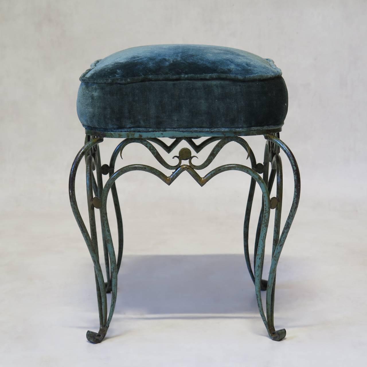 Delightful pair of petite wrought iron stools in the style of René Drouet and René Prou. The iron bases feature exaggerated cabriole legs ending in scrolled feet and are painted in the original verdigris color, with details highlighted in gold.