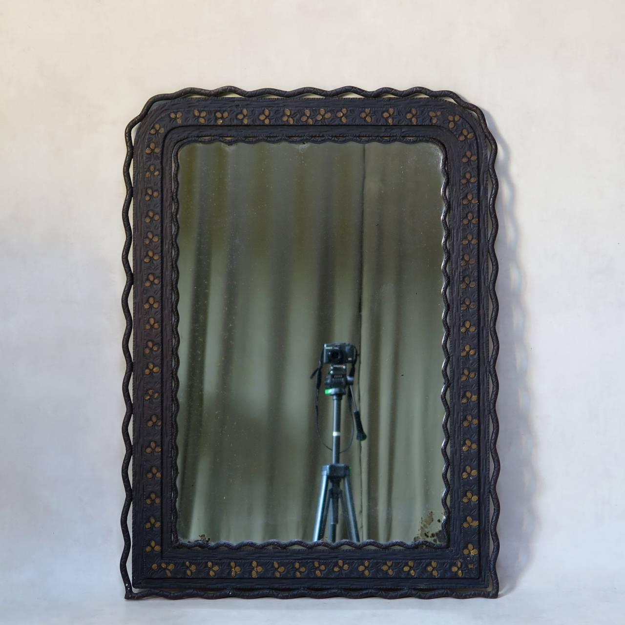 Delightful, charming and unusual mirror and chair set. 

The mirror is of very heavy wrought iron. The frame is stamped with a floral frieze motif with gilded accents and wavy scalloped edges on the inside and exterior. Rounded top corners.