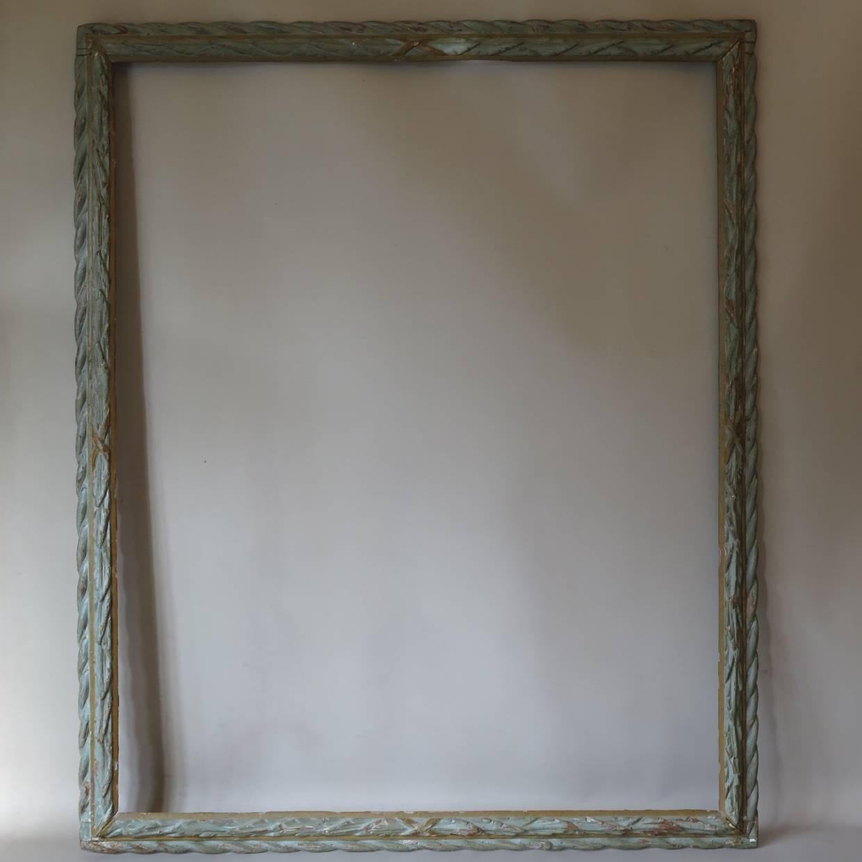 Beautiful large frame with a carved laurel leaf wreath motif, painted light green, with gold-colored crossed ribbons.