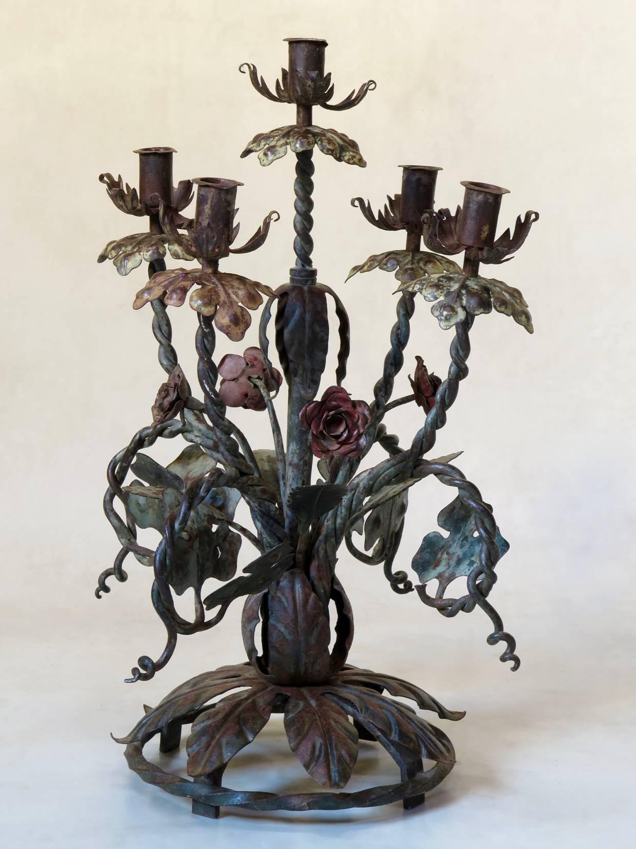 Gorgeous and heavy pair of handcrafted iron candleholders, with a decor of vines, leaves and flowers in faded green, pink, yellow and cream colors. Each piece holds five candles.