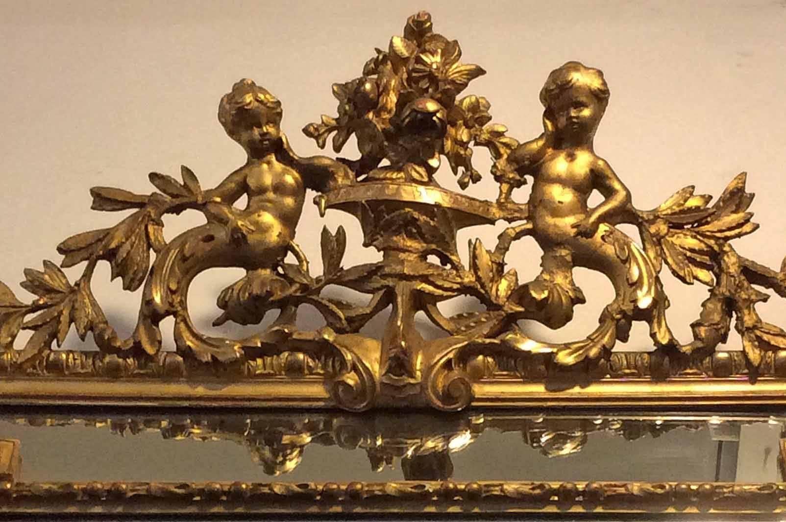 French gold gilt mirror features cherubs and a beveled glass.

 Origin: France,
circa 1870s.

 Measurements: 43 1/4