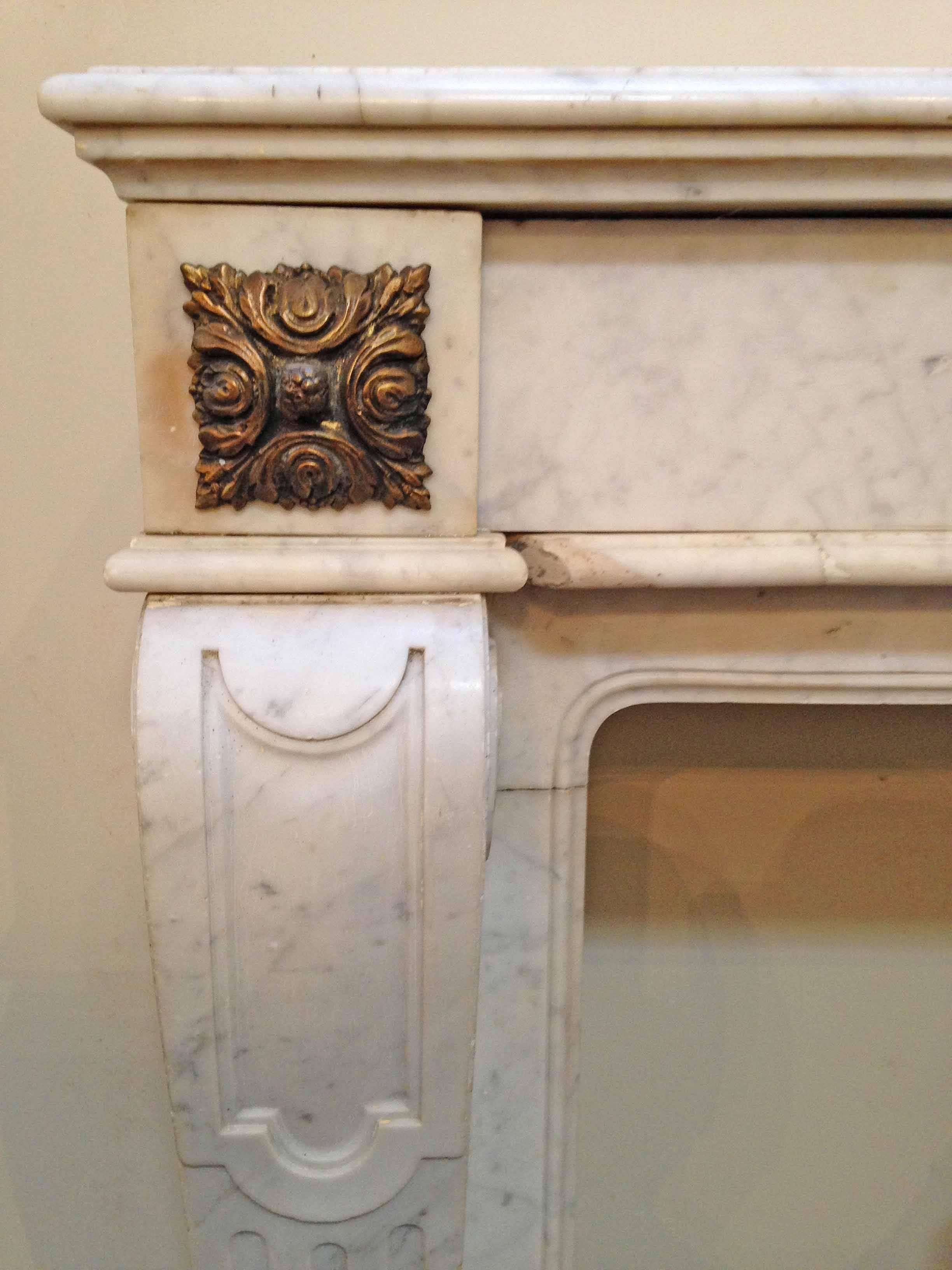 Made from Carrara marble, this lovely mantel showcases a copper medallion that appears to reflect two winged animals sipping from a fountain. On top of each leg sits a copper floral embellishment. The legs have revers fluting and a scroll-like curve