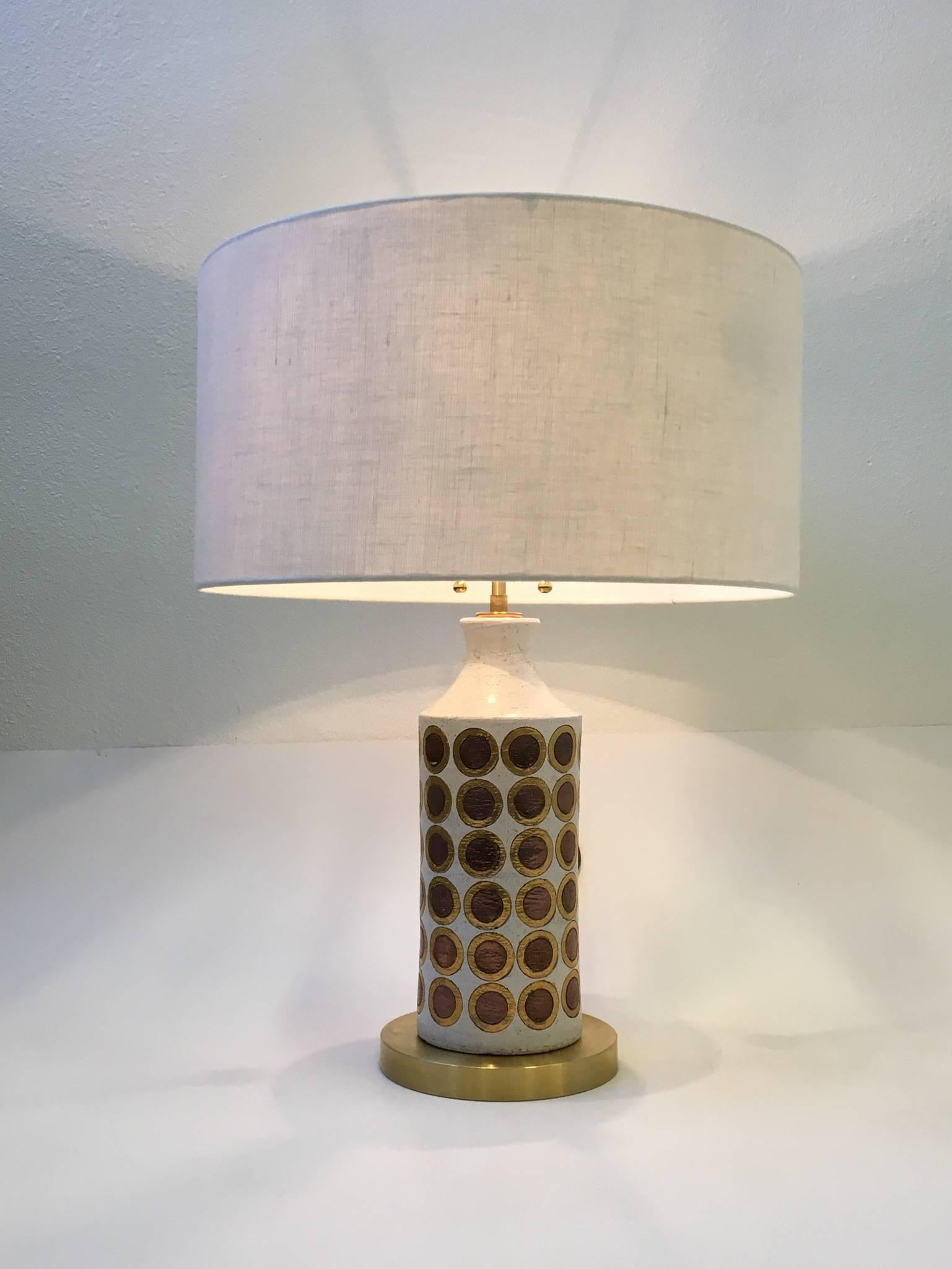 A rare 1960s Italian ceramic table lamp by Bitossi. The lamp has beautiful circles glazed in gold and copper with a white background. Newly rewired with all new brass hardware, brown cloth cord and new vanilla linen shade. 
Dimensions: 26.5