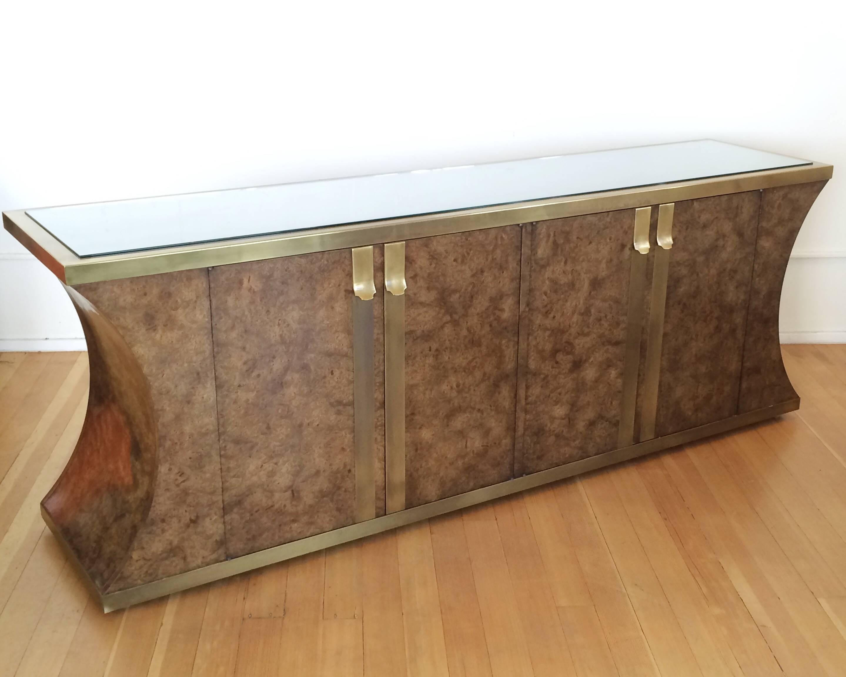 Dark Burlwood credenza framed with aged brass at the top and bottom. 
Also has aged brass pulls and strips on the doors. 
Inside has four drawers on one side and one adjustable shelf on the other. 
New 1/4