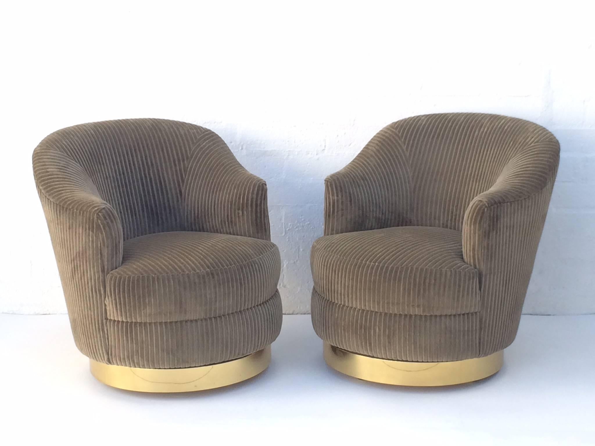 This beautifully design chairs have been upholster in a light brown thick soft corduroy fabric that enhances the lines of the chair. The solid polished brass swivel base with casters are in excellent condition.