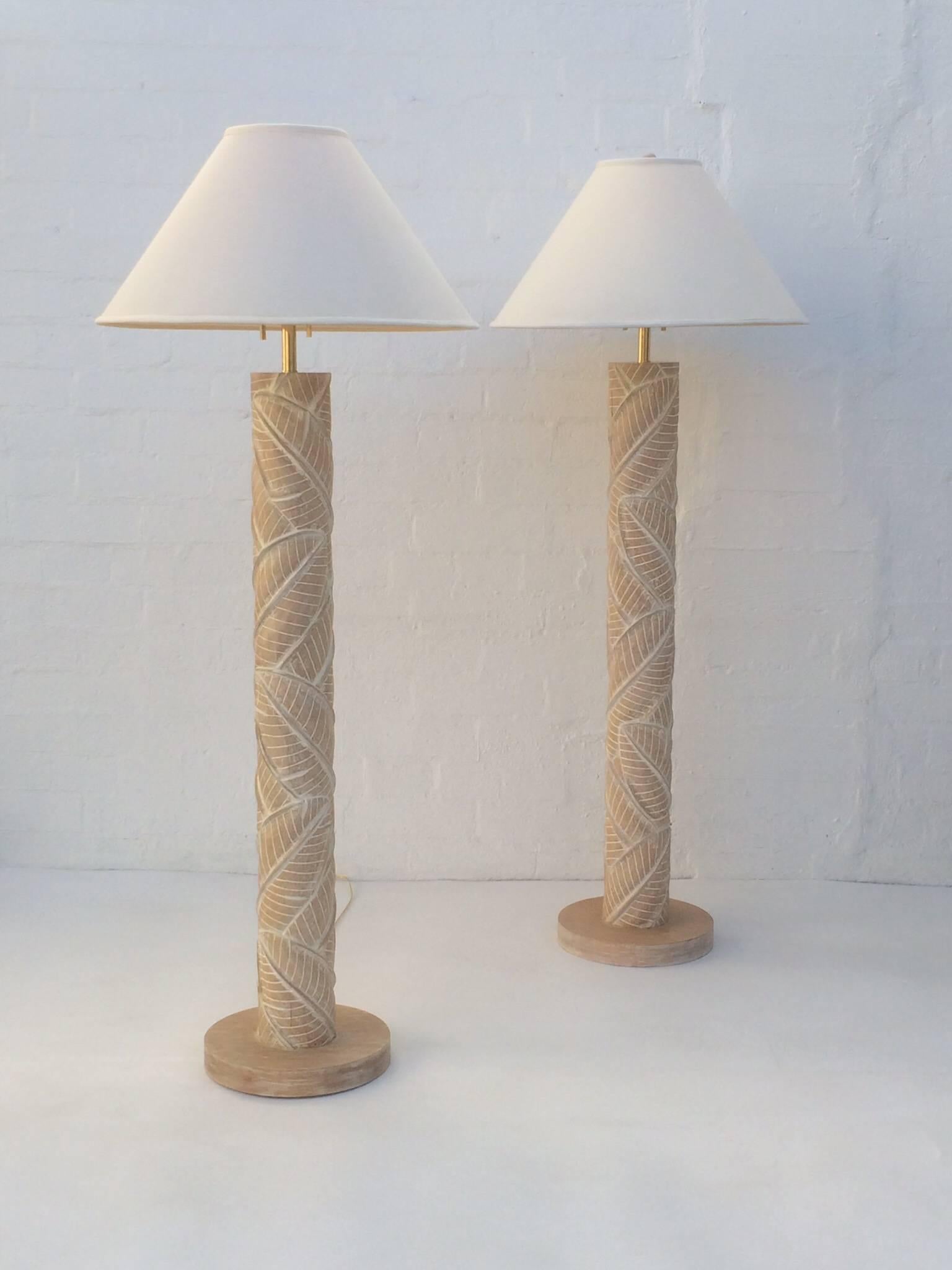 A beautiful pair of carved wood leaf pattern floor lamps.  
Newly re-wired with new brass hardware and new linen shades.  
These lamps came out of a Steve Chase designed Estate in Plam Desert California that was done in the 1970s. .