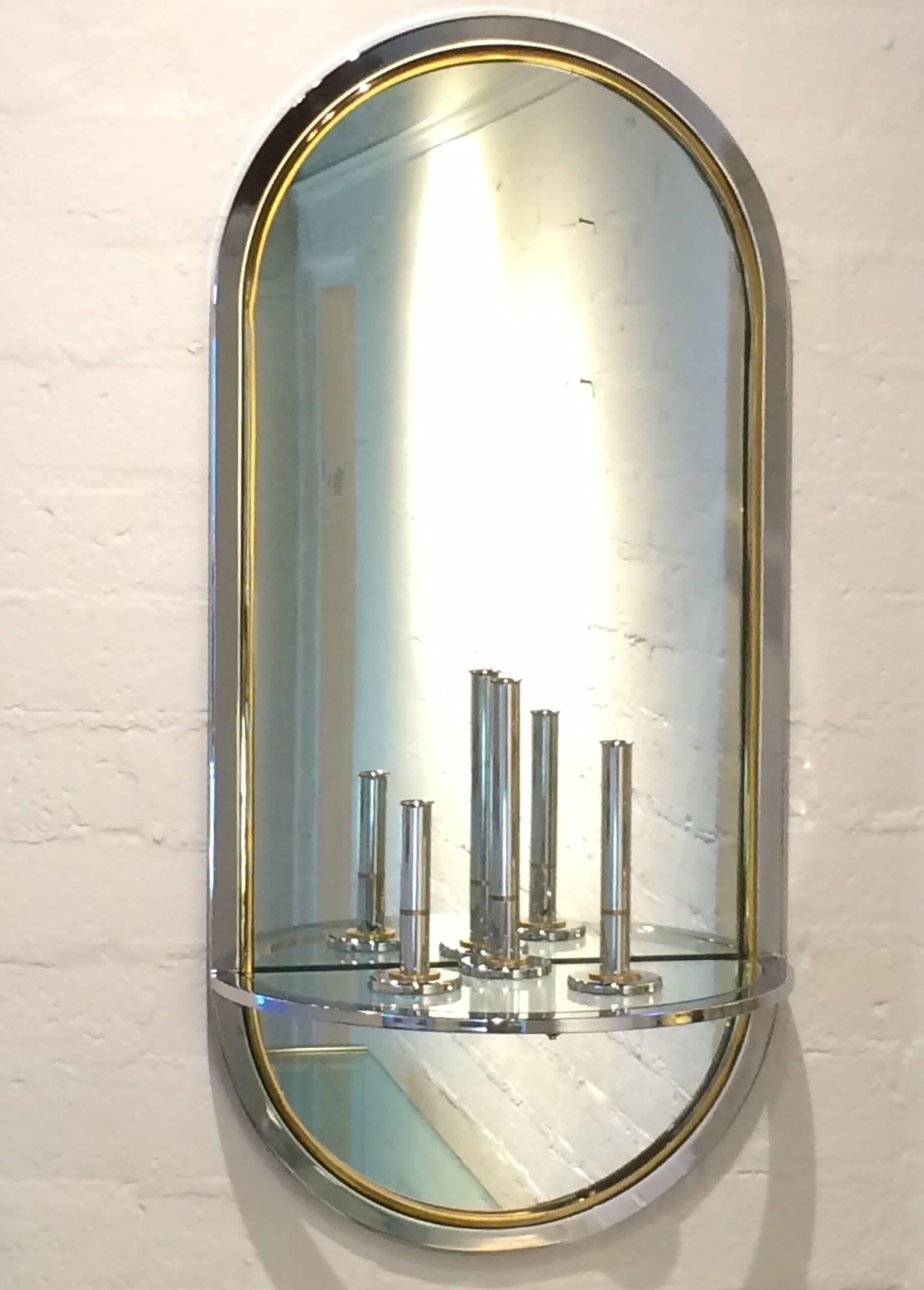 Racetrack shaped wall mirror with glass inset demilune shelf.
Framed with a chrome and brass band. 
Made by Pace Collection.