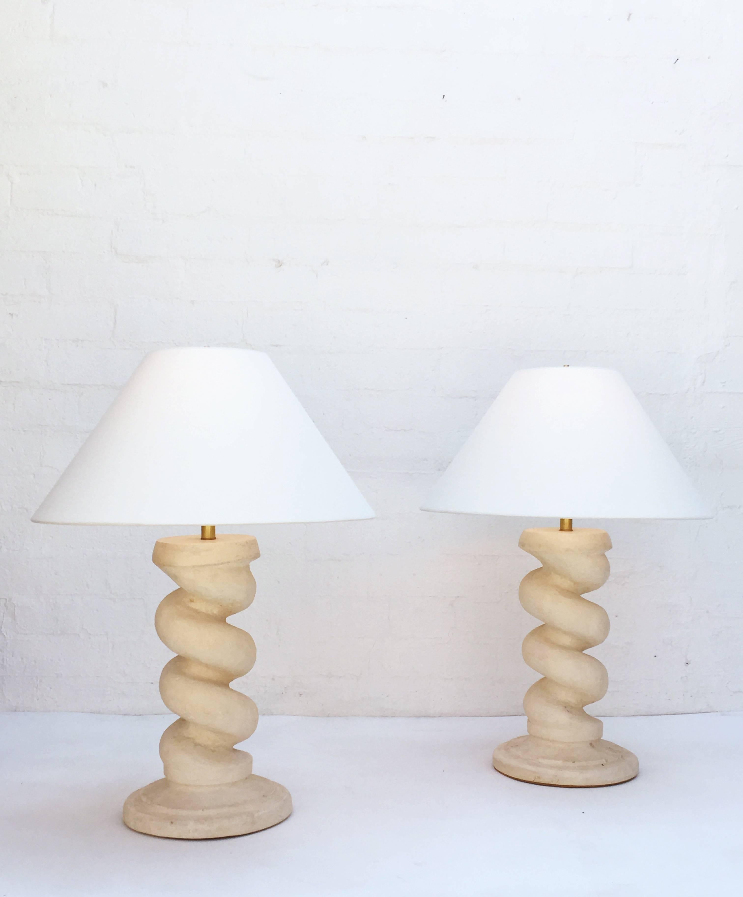 Beautiful heavy cast plaster spiral column table lamps designed in the 1960s by Michael Taylor. Newly rewired with brass hardware and new linen shades.
The base is 12