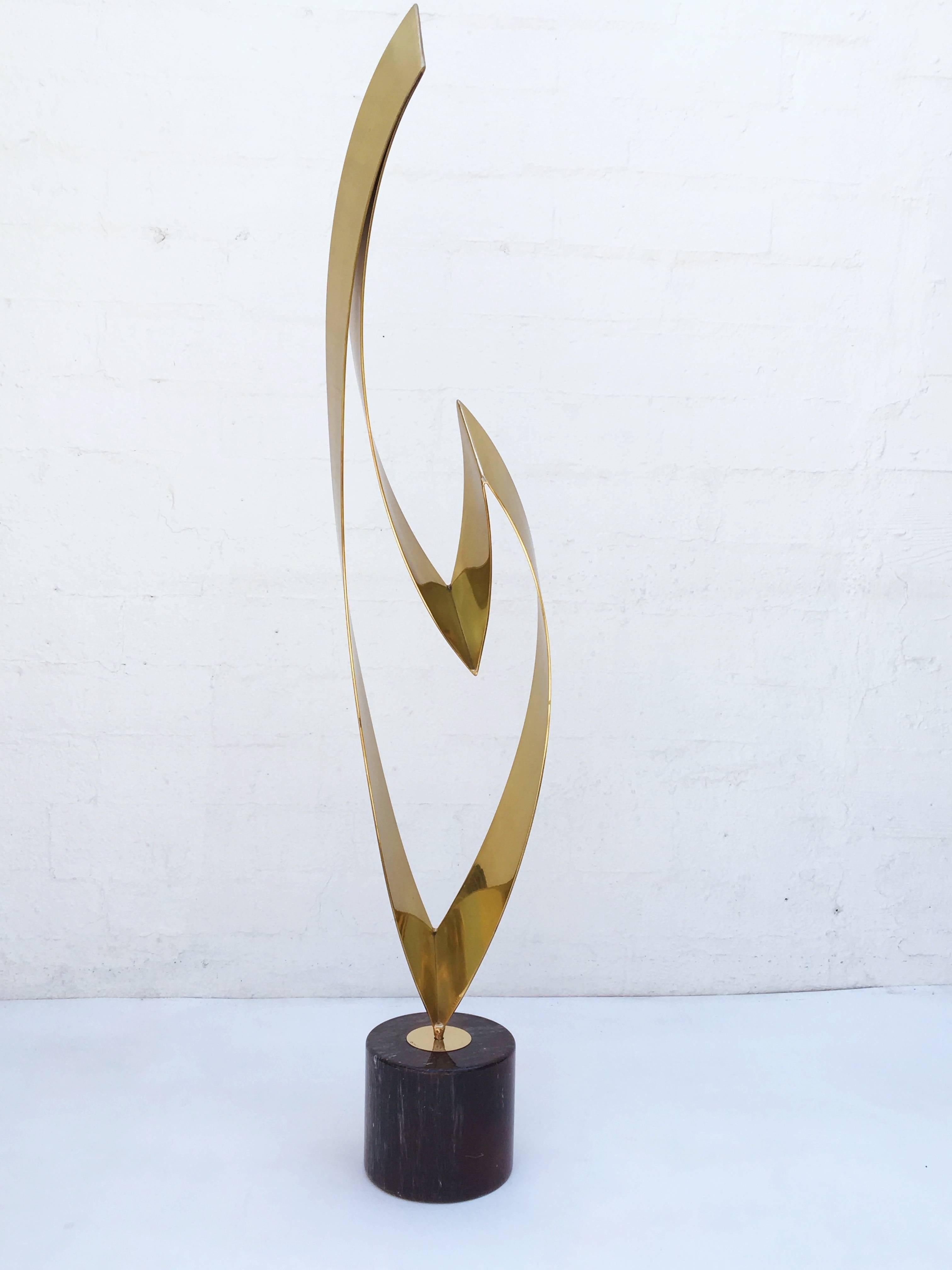 A beautiful polished brass abstract sculpture on a black marble base designed by Curtis Jere' in the 1970s. The sculpture is signed on the base.

The base is 7