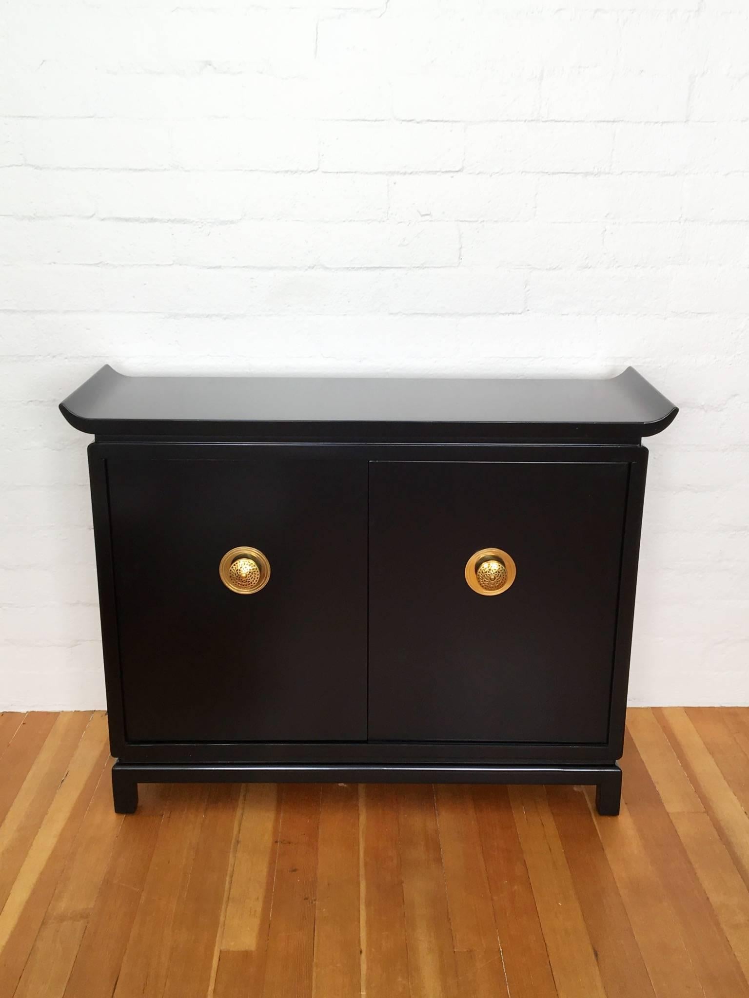 1950s black lacquered cabinet with brass pulls. The inside is red lacquered with one adjustable shelf and its signed on one-door James Mont Design.