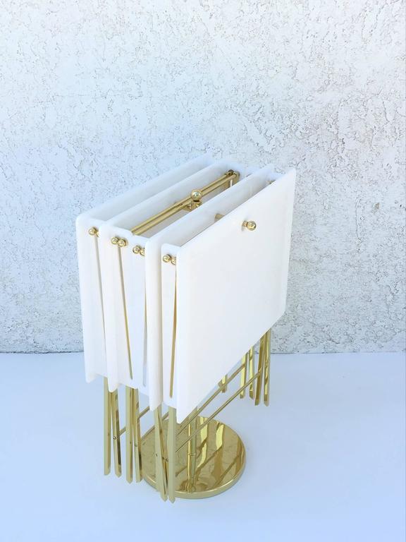 A glamorous set of four white acrylic and polished brass folding tray tables designed in the 1960s by Charles Hollis Jones.

New tops and newly re-plated.
Diameter: Length 22", height 24", depth 14".