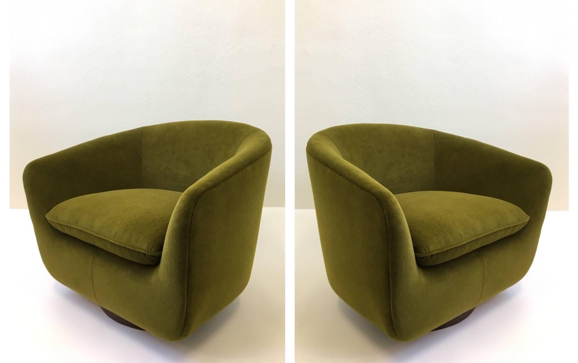 A pair of spectacular swivle lounge chairs designed by Edward Wormley for Dunbar. This chairs are newly reupholstered in a beautiful soft olive green Mohair fabric. The dark walnut wood base is in original finish. 

Dimensions: 28