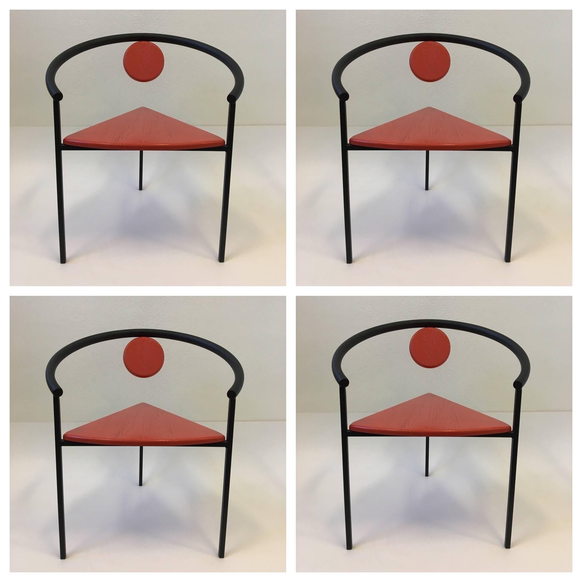 A beautiful set of four steel and wood dining chairs from the Memphis period in the manner of Italian designer Michele De Lucchi. Newly powder coated satin black and the seat and back wood rest is newly lacquered in a red orange color. (see detail